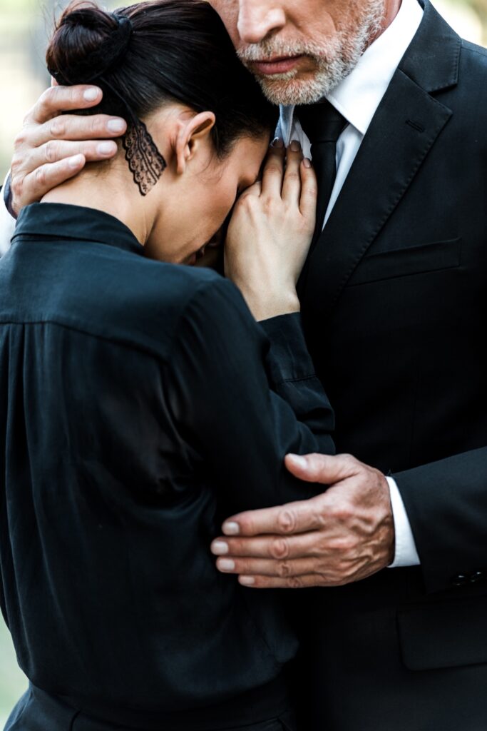 cropped view of upset senior man hugging woman on funeral